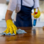 Close-up on a professional cleaner cleaning a table at a house - housework concepts