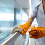 Close-up on a cleaner working at a hospital and cleaning a handrail - janitorial service concepts