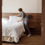 Housekeeper cleaning a hotel room. Maid making bed in hotel room. Staff maid making bed.